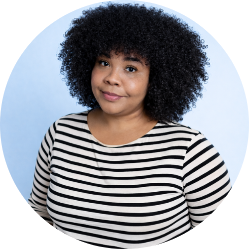 Professional headshot of Rayna Watson, a digital marketer and graphic designer, wearing a black-and-white striped shirt, with natural curly hair, photographed against a soft blue background.
